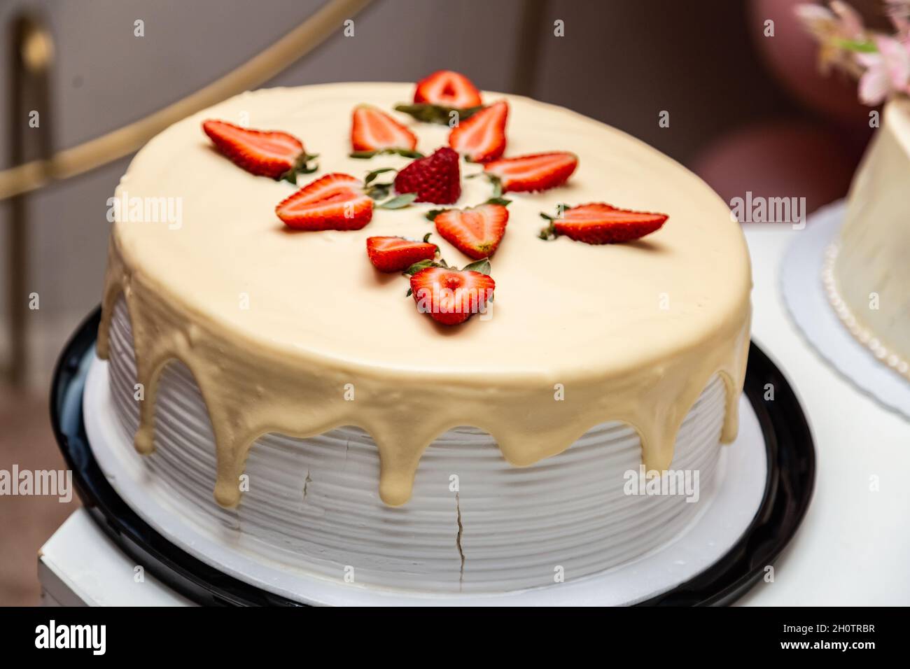 Torta decorata con glassa e fragole su un tavolo decorato per una festa di compleanno. Foto Stock