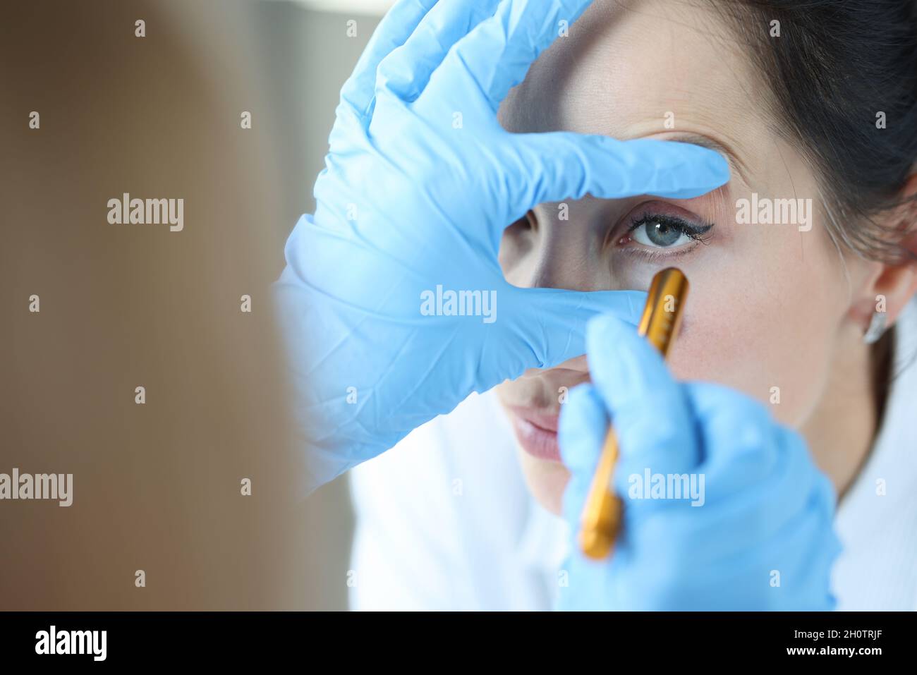 Il medico illumina l'occhio del paziente per controllare il primo piano della pupilla Foto Stock