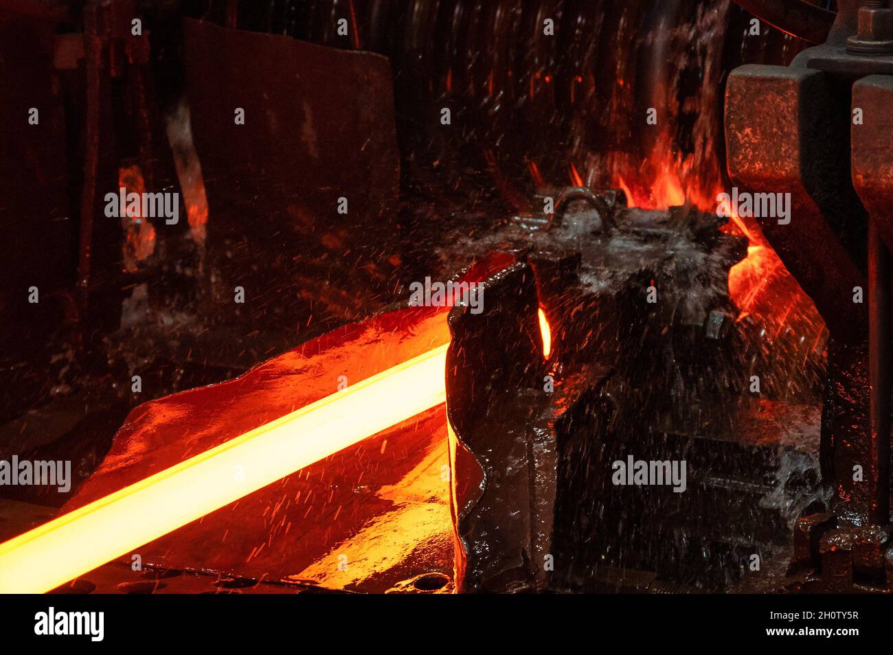 La barra di metallo rosso-caldo è arrotolata su un laminatoio Foto Stock