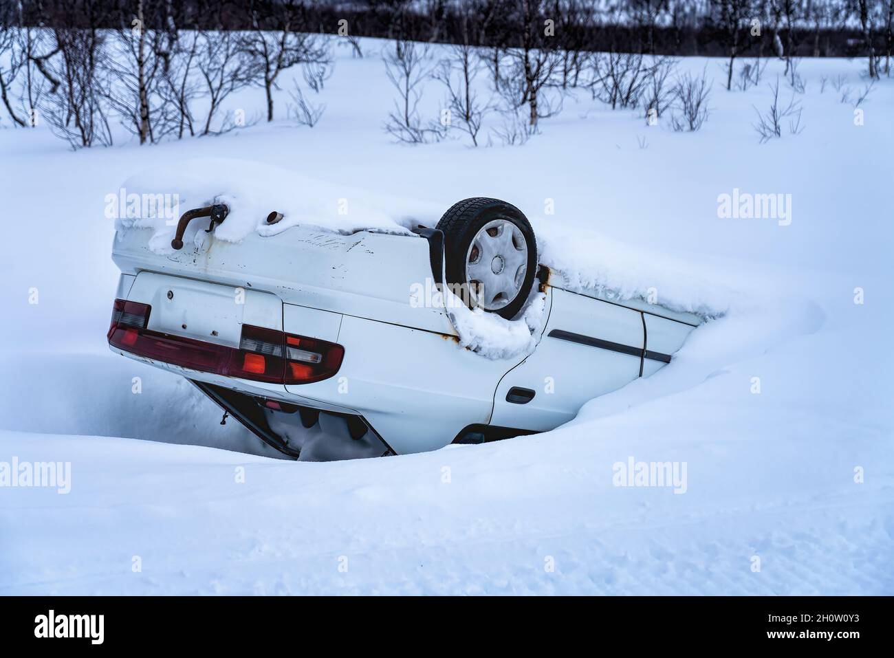 Auto ribaltata dopo incidente in montagna in neve profonda dopo nevicate, vista posteriore, auto di strada di montagna ghiacciata scivolosa Foto Stock