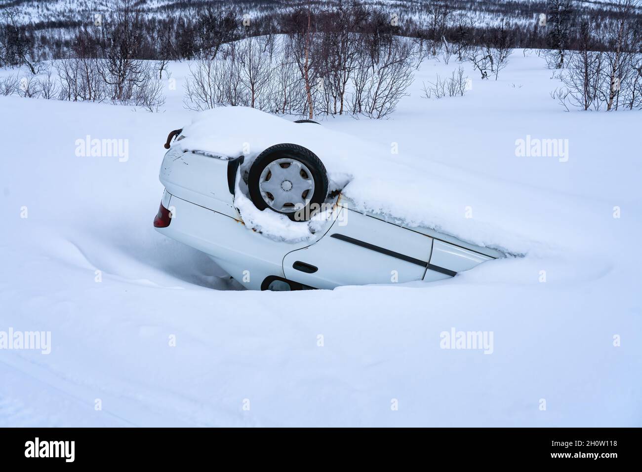 Auto ribaltata dopo incidente in montagna in neve profonda dopo nevicate, vista laterale, auto di strada di montagna ghiacciata scivolosa Foto Stock