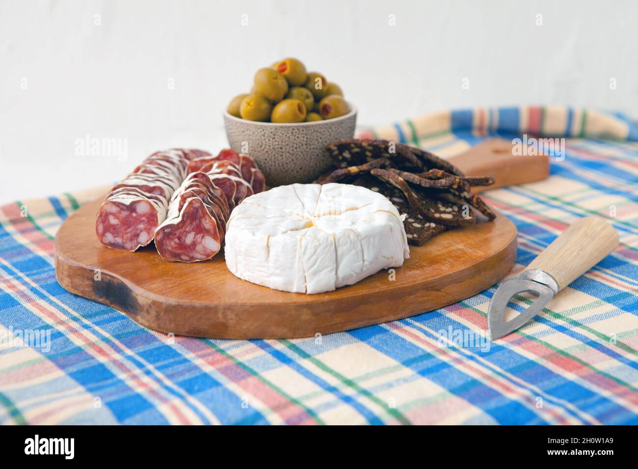 merenda semplice con camembert formaggio, olive e pane con prosciutto su tessuto blu sfondo, stile retrò Foto Stock
