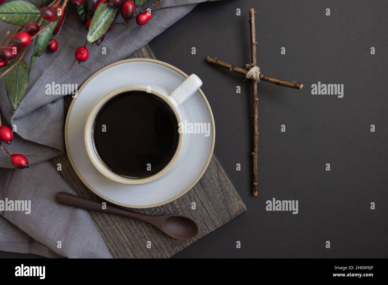 Tazza di caffè e croce di legno con bordo di Natale su sfondo nero con spazio copia Foto Stock