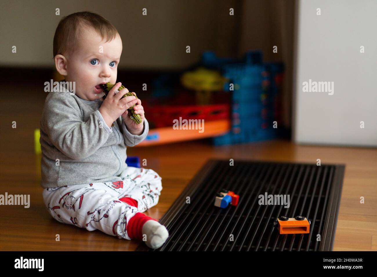Bambino piccolo e carino seduto sul pavimento e giocare a giocattoli Foto Stock