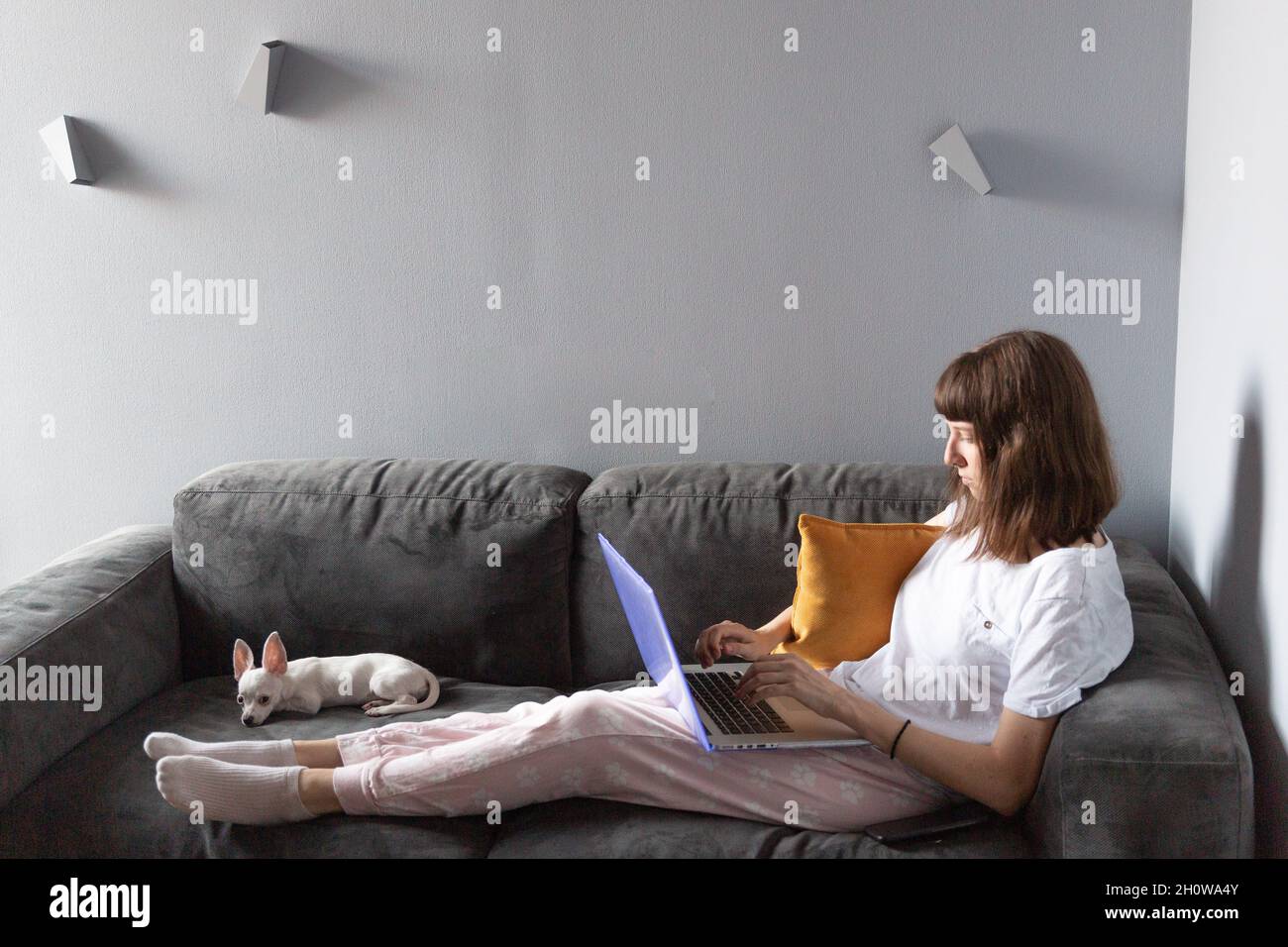 Vista della donna con computer portatile sdraiato sul divano Foto Stock