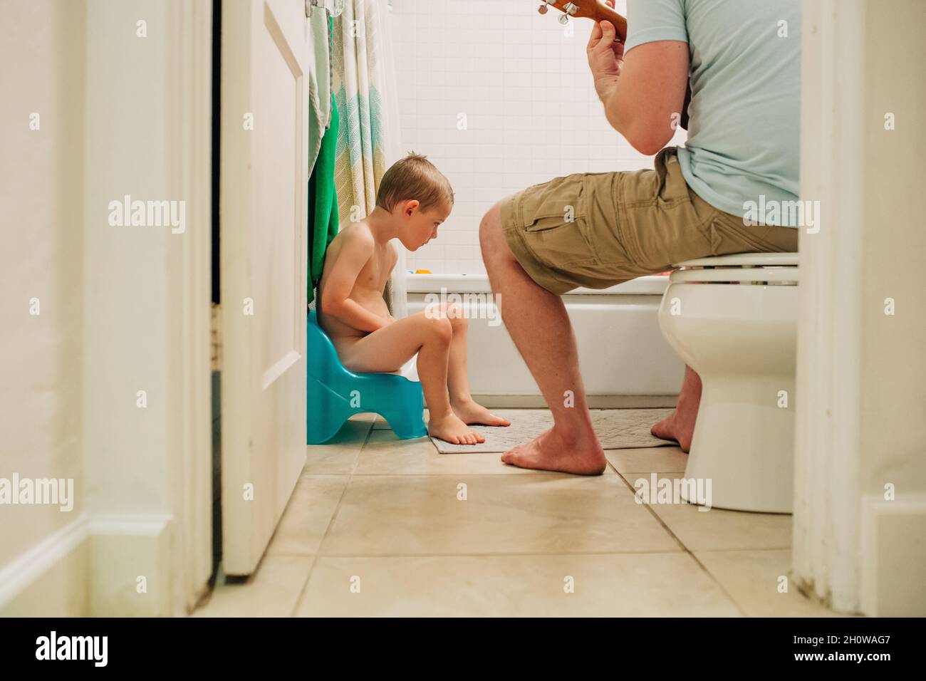 Ragazzo di quattro anni imparando ad addestrare potty con il papà che aiuta Foto Stock