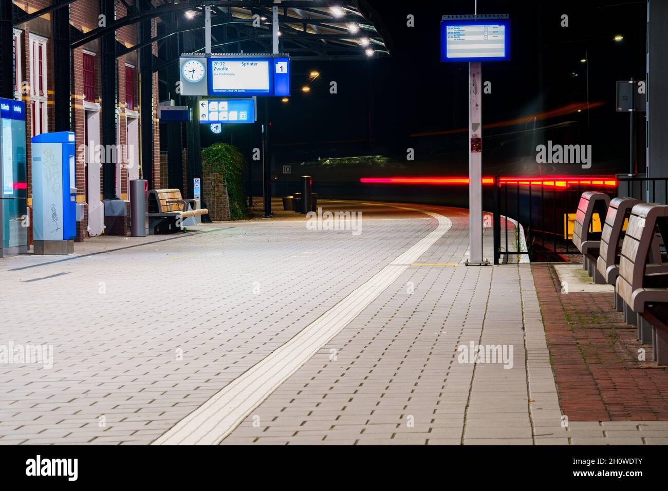 Leggero sentiero del treno locale nella stazione ferroviaria di notte Foto Stock