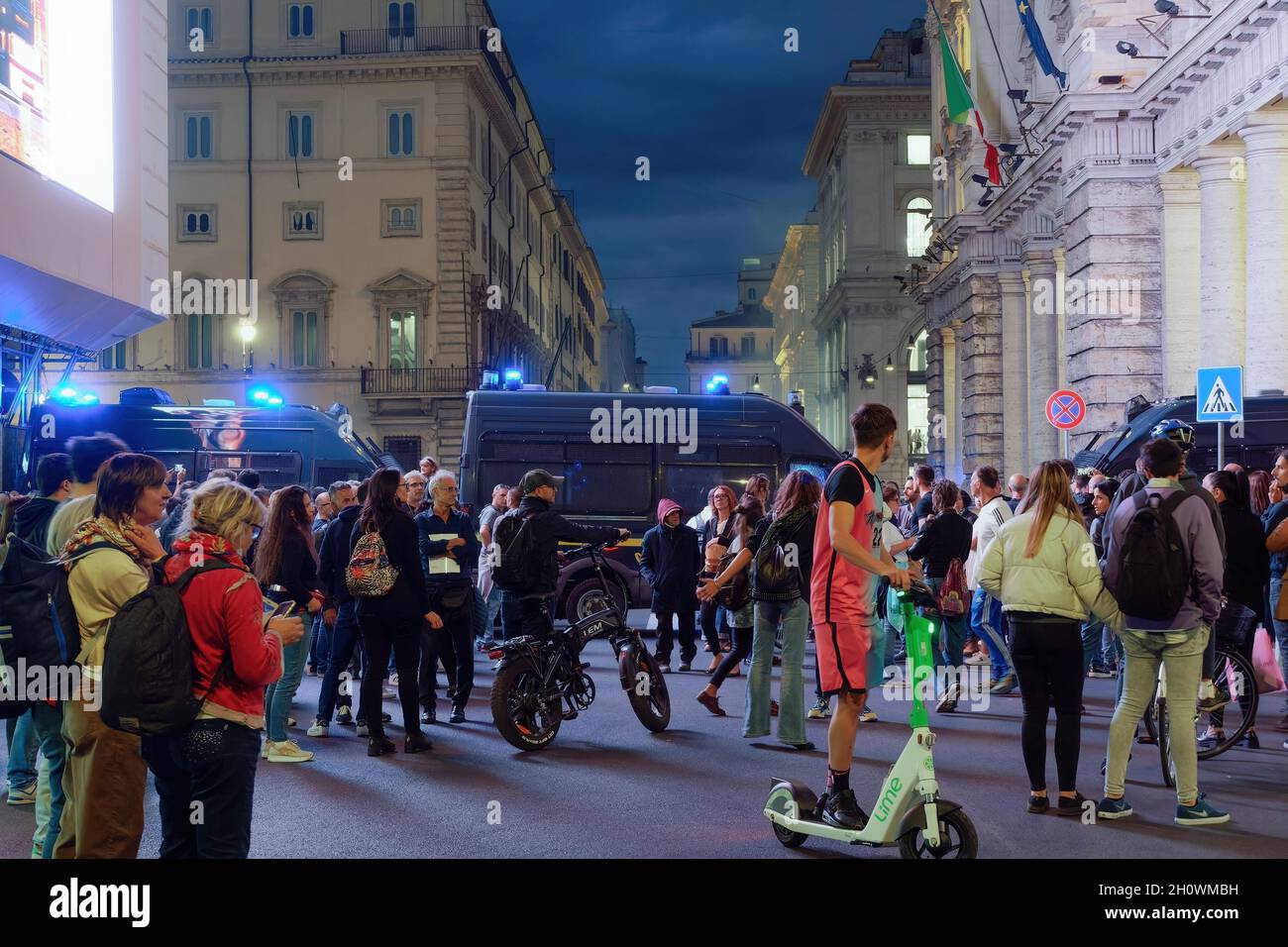 Roma, Italia - 9 ottobre 2021: Protesta anti-vax contro l'estensione del sistema di pass sanitario COVID-19. Radunata folla di passaggio prima di veicoli di polizia sommossa, con i manifestanti contro il verde passare dietro. Foto Stock