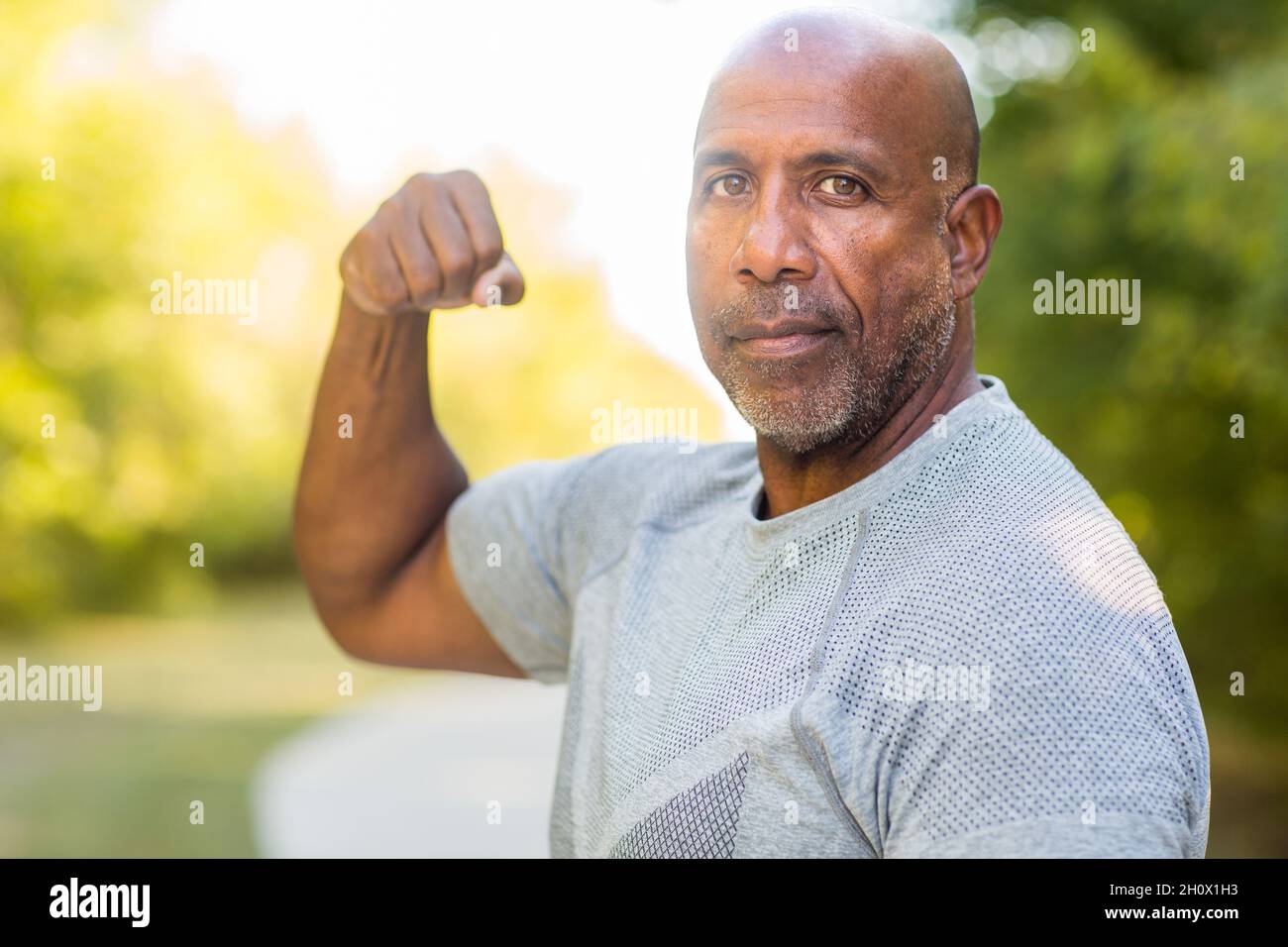 Matura afroamericana che flette il suo muscolo bicep. Foto Stock