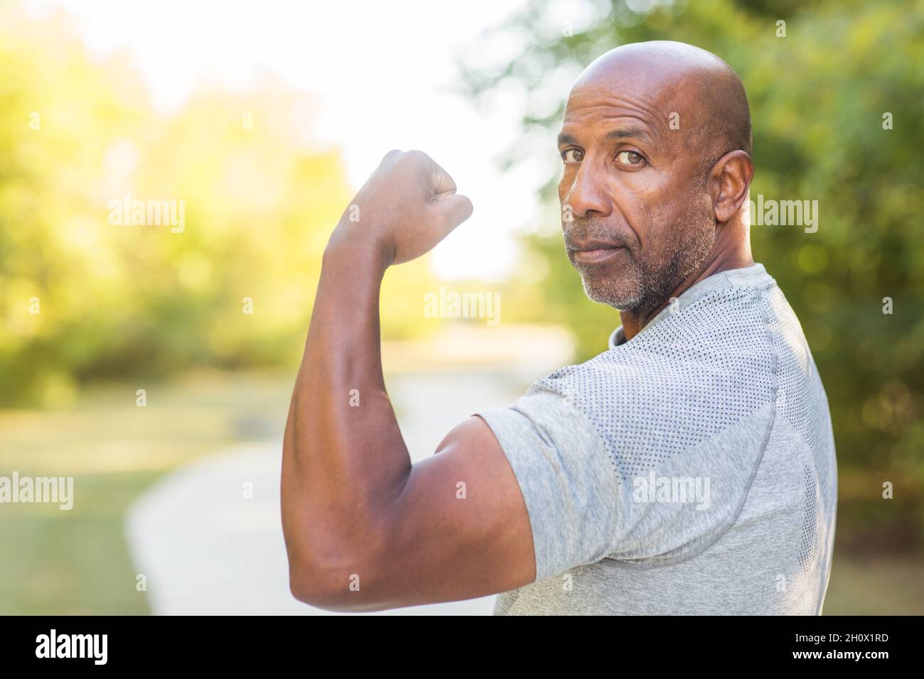 Matura afroamericana che flette il suo muscolo bicep. Foto Stock