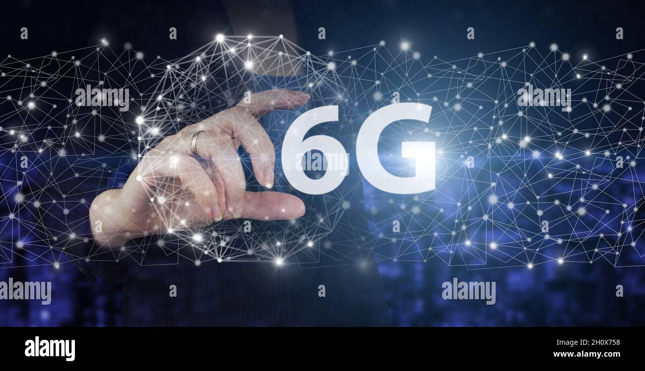 Componenti della tecnologia di comunicazione dei sistemi 6G. Mano Hold digitale ologramma 6G segno sulla città scuro sfondo sfocato. Sistemi wireless e Internet di t Foto Stock