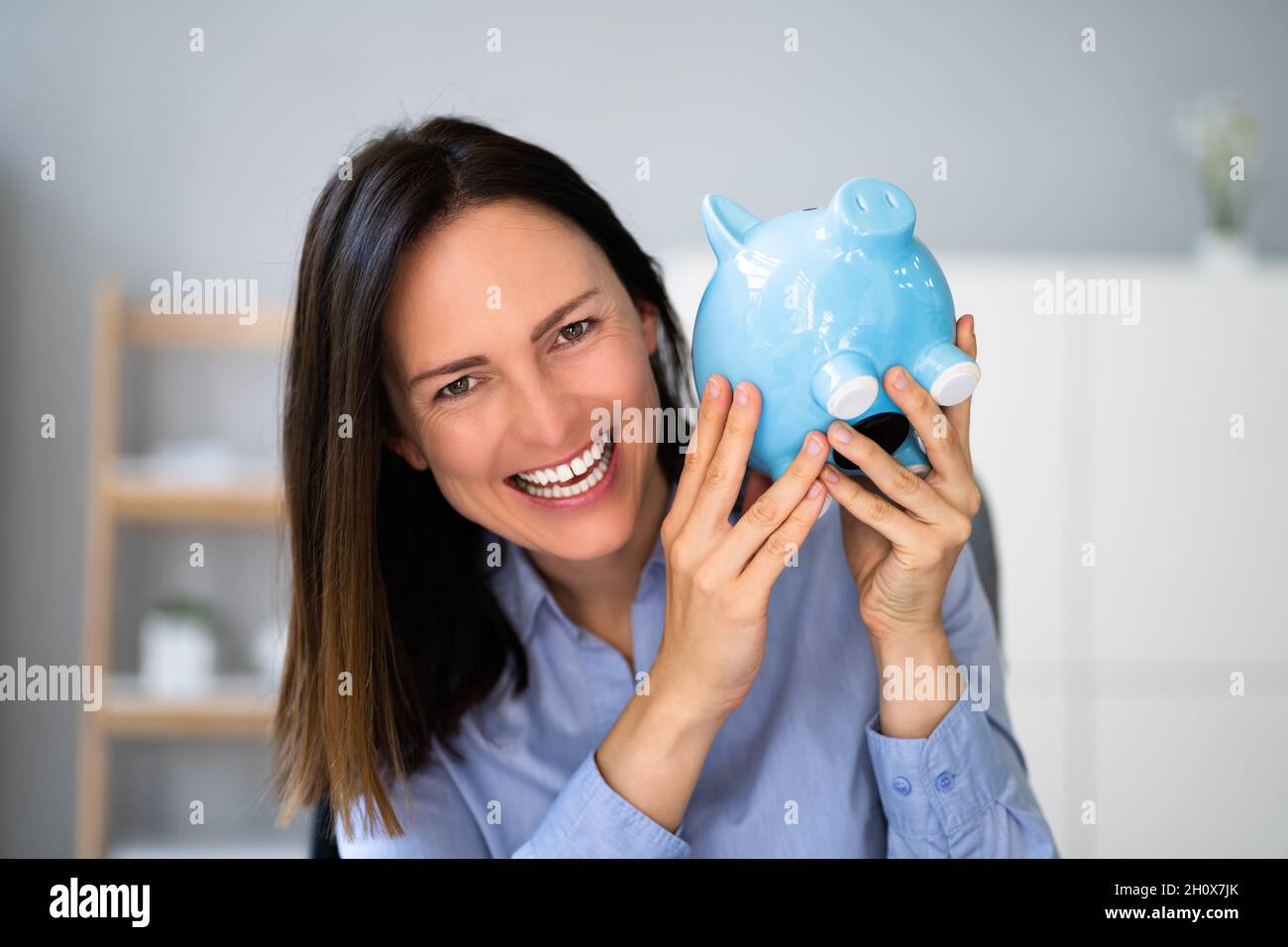 Felice risparmio di denaro giovane donna con Piggy Banca di sicurezza Foto Stock