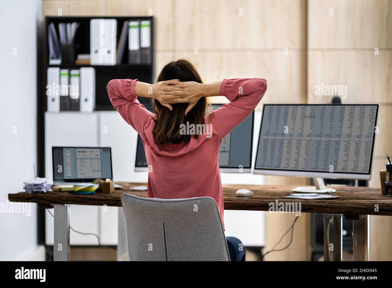 Donna di affari che fa l'esercitazione stretch alla scrivania dell'ufficio Foto Stock