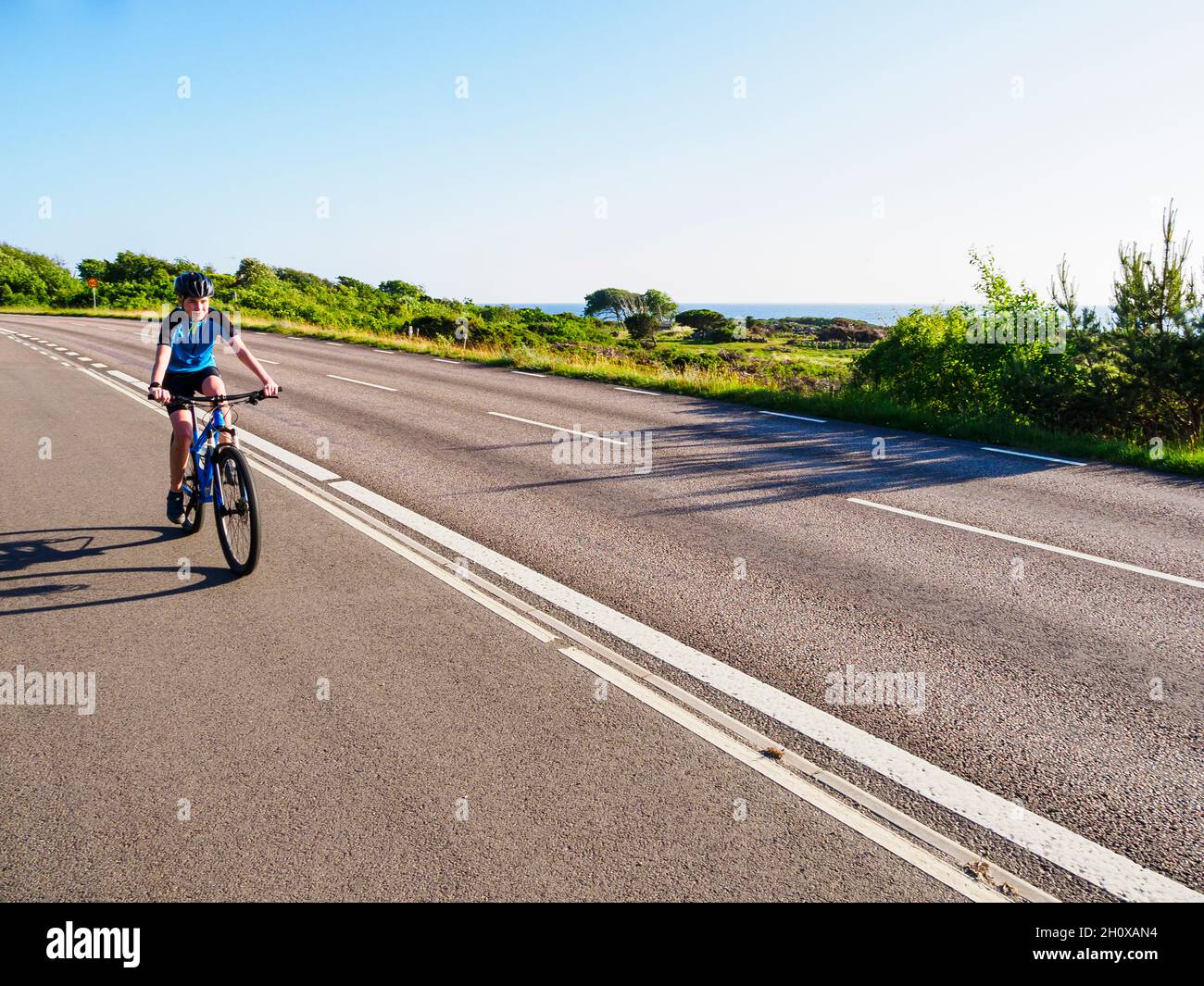 Ragazzo in bicicletta lungo la strada di campagna Foto Stock