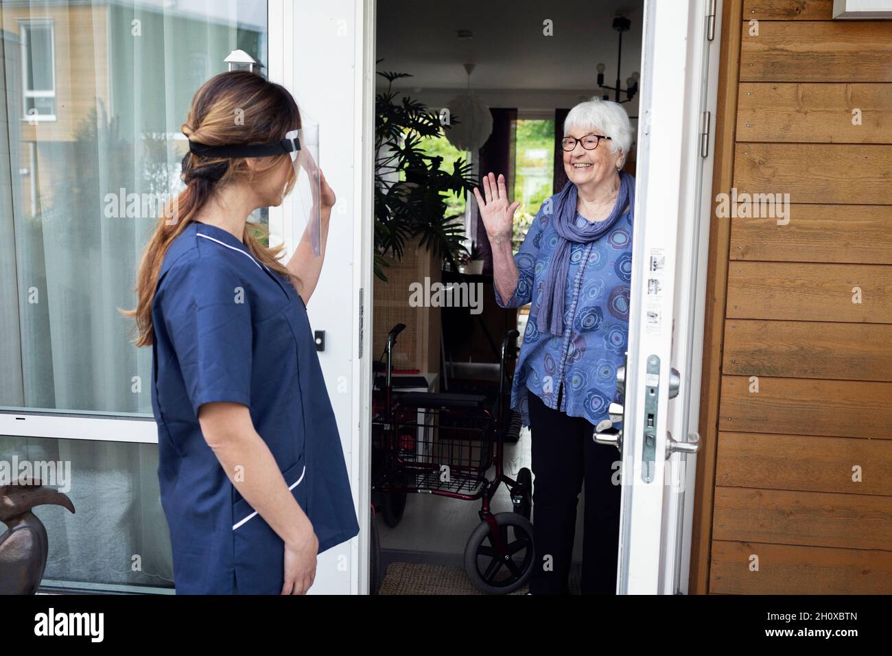 Infermiera donna saluto a casa Foto Stock