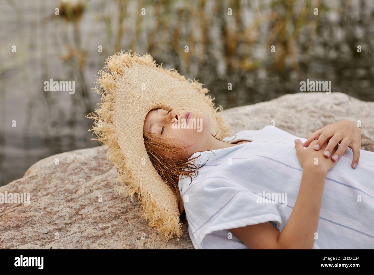 Ragazza che indossa cappello di paglia che riposa sul lago Foto Stock