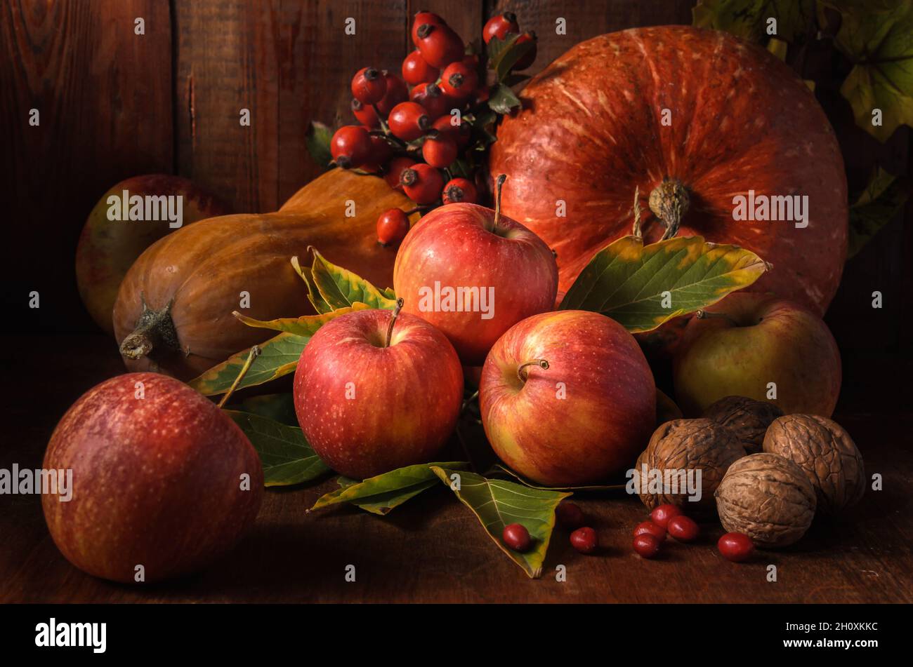 mele e altri frutti su sfondo di legno scuro in stile rustico Foto Stock