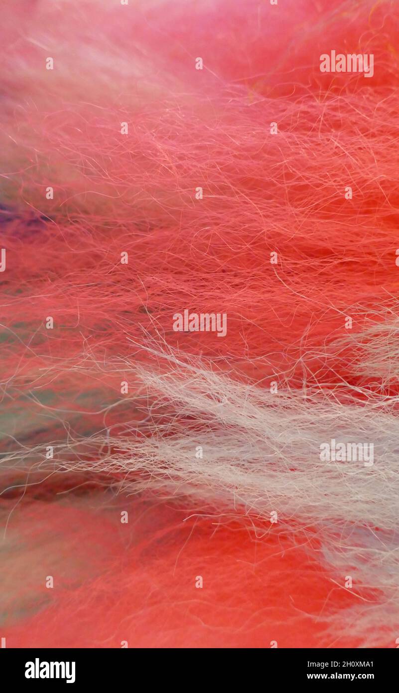 Immagine verticale di fili morbidi di lana nei colori rosso, rosa, bianco e un po' di viola Foto Stock