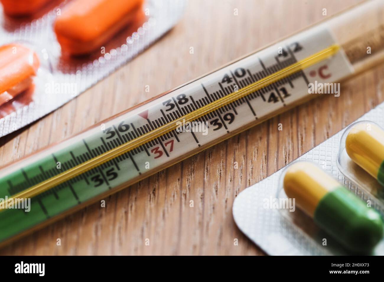 Termometro medico a mercurio e confezione con pillole sul tavolo - virus influenzale stagionale Foto Stock