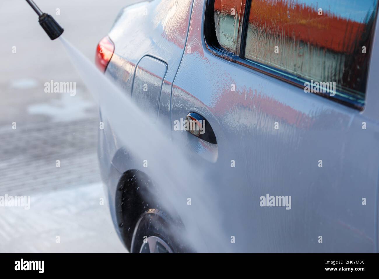 mano con lavatrice ad alta pressione lavaggio auto bianca presso la stazione di lavaggio auto pubblico self-service Foto Stock