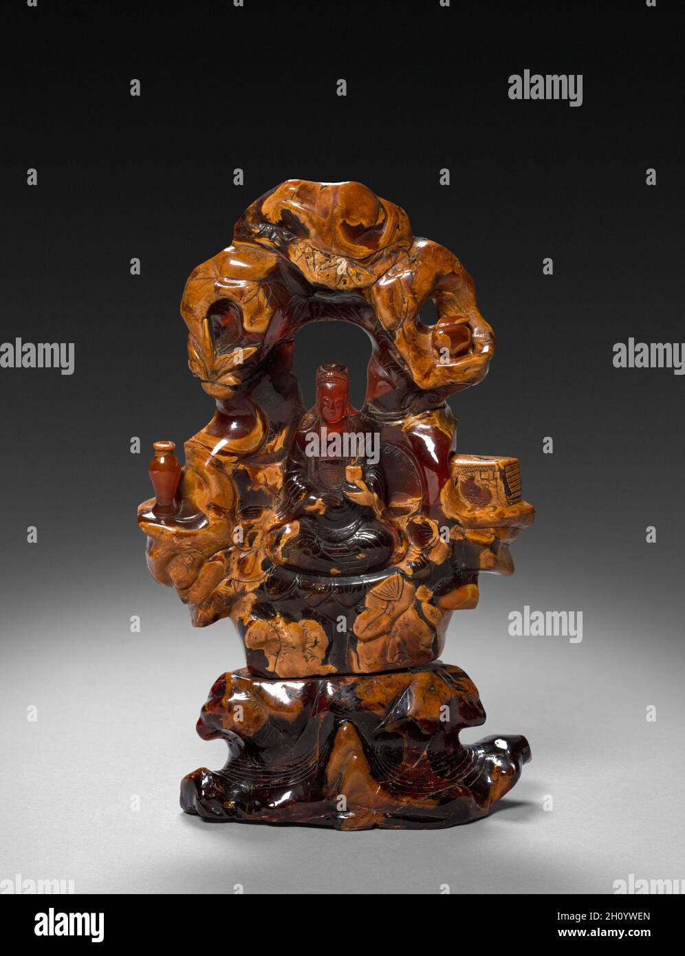 Bodhisattva Guanyin seduto in una roccia Grove, 1675-1700. Cina, dinastia Qing (1644-1911). Ocra opaco e traslucido rosso-arancione ambra; complessivo: 22,9 cm (9 in.). Foto Stock