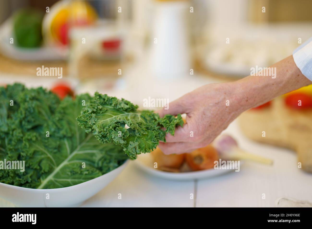 Vecchia donna irriconoscibile che prepara l'insalata di verdure mentre cucinano il cibo in cucina a casa Foto Stock