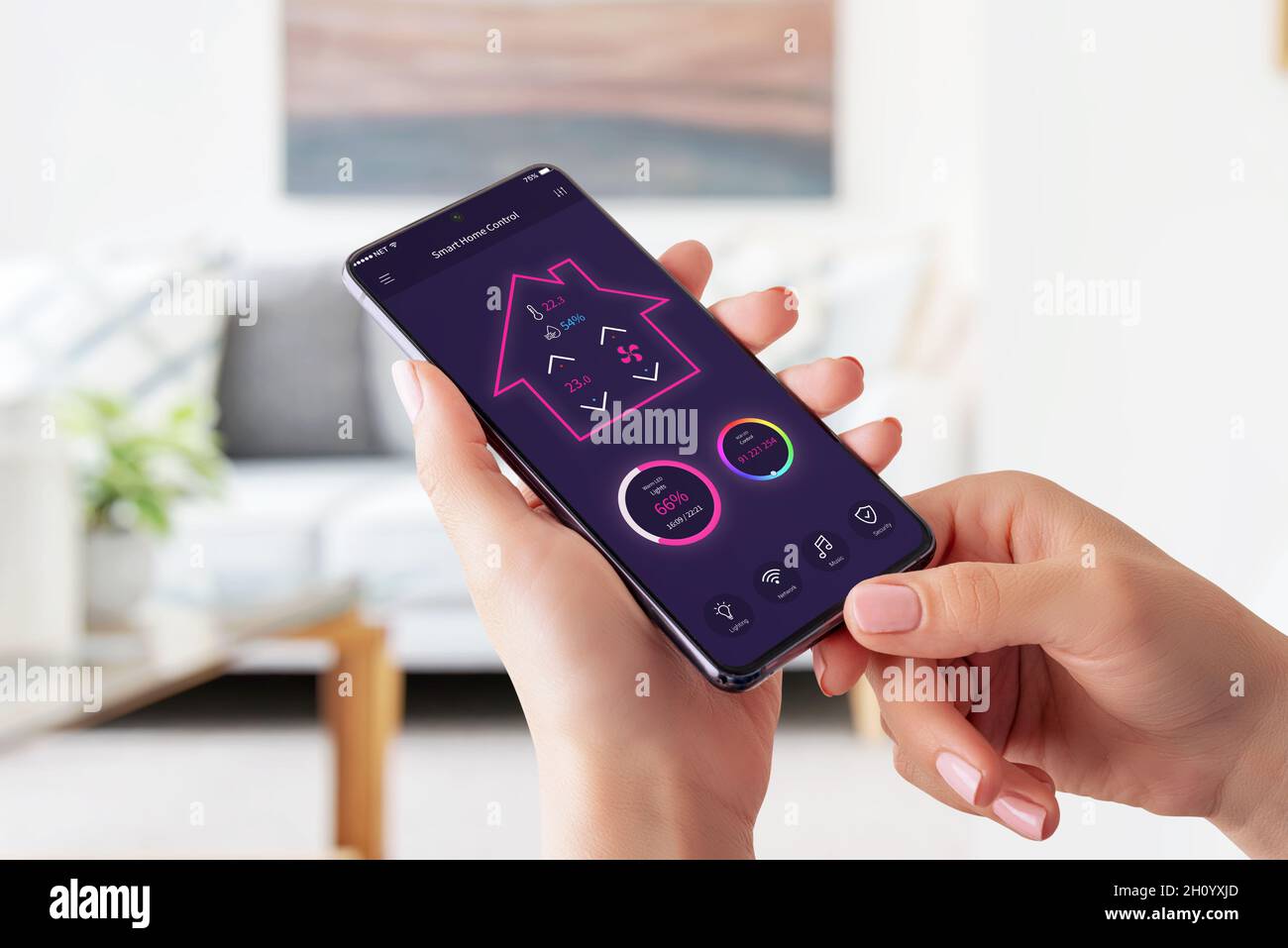 Moderna app di controllo intelligente della casa sul concetto di smartphone. Donna che tiene smartphone e controlla la temperatura, la luce, la musica e il sistema di sicurezza Foto Stock