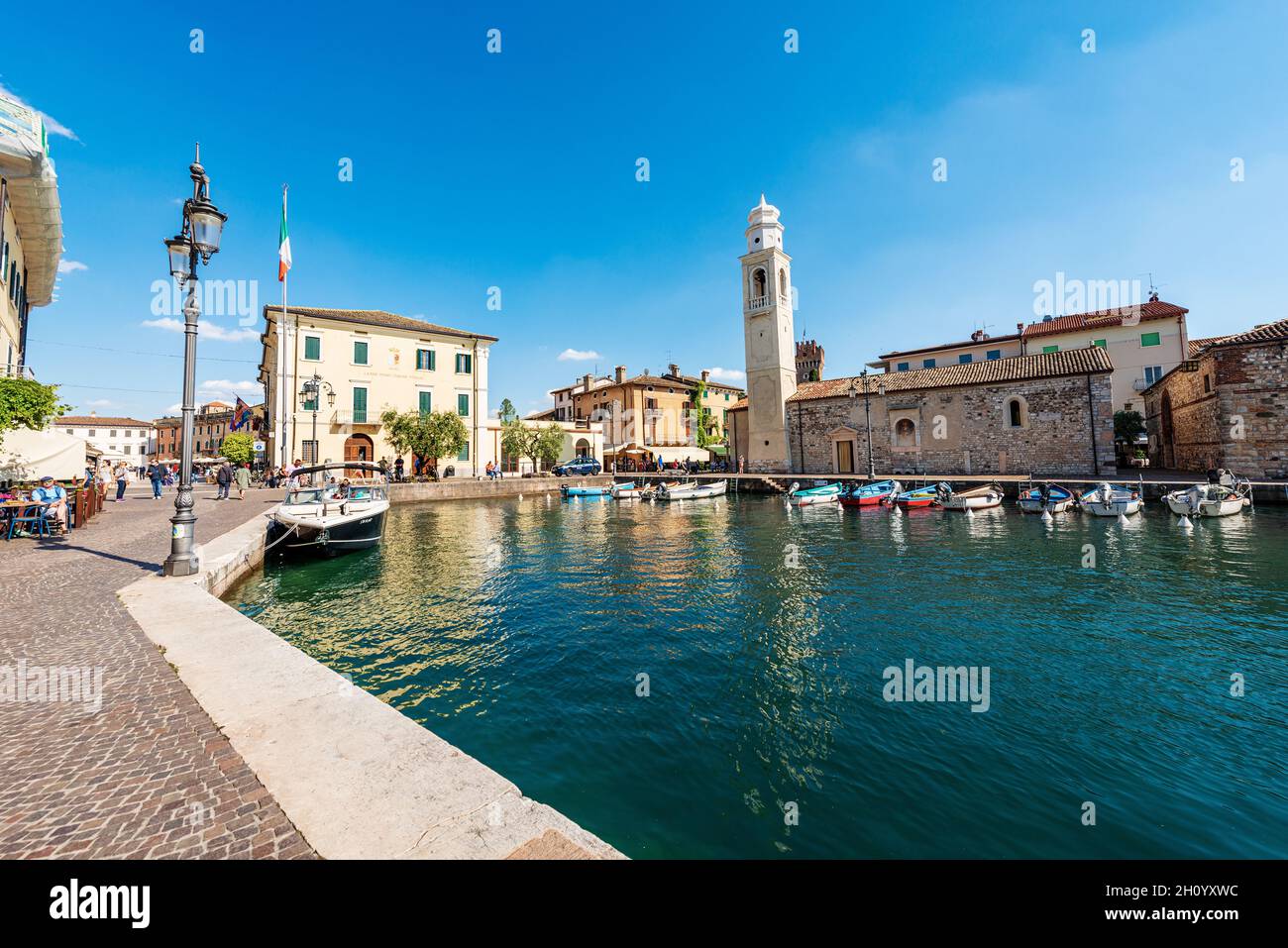 Porto del piccolo borgo di Lazise, località turistica sulla costa del Lago di Garda (Lago di Garda). Chiesa di San Nicolo in stile romanico. Verona, Italia. Foto Stock