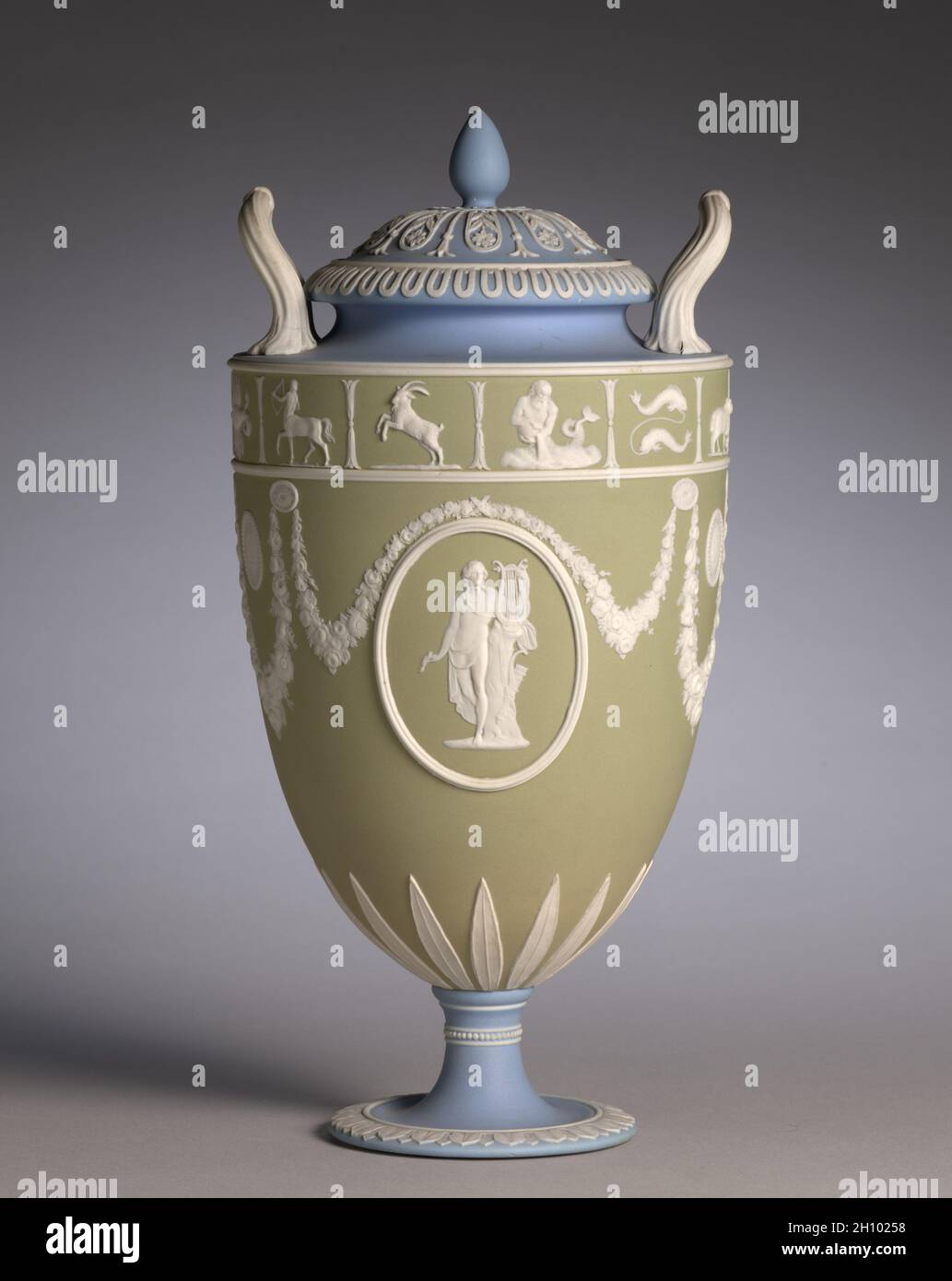 Covered Vase (uno di un paio), c.. 1850. Josiah Wedgwood e figli (britannici, Staffordshire, est. 1759). Vasellame con decorazione a rilievo; totale: 29.9 cm (11 3/4 poll.). La giaspera tricolore di Wedgwood divenne popolare per la prima volta nel 1770 durante un periodo di fascino con decorazione neoclassica. Questo vaso è stato probabilmente fatto intorno al 1850 durante il periodo in cui questo tipo di decorazione è stato ravvivato. I medaglioni di rilievo raffigurano due versioni del dio greco Apollo, il dio della musica, accanto alla sua arpa o lira. Foto Stock