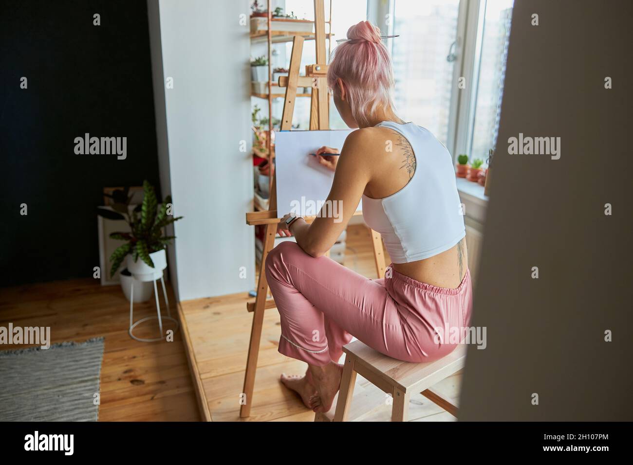 Donna artista in abiti casual al lavoro su foto su tela bianca a casa Foto Stock