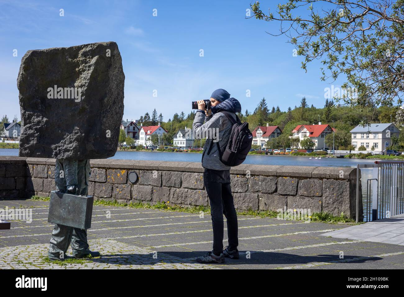 REYKJAVIK, ISLANDA - 12 giugno 2021: Un turista che scatta una foto di un 'Monumento al burocrate ignoto' di Magnus Tomasson, sul bordo del lago Tjornyn. Foto Stock