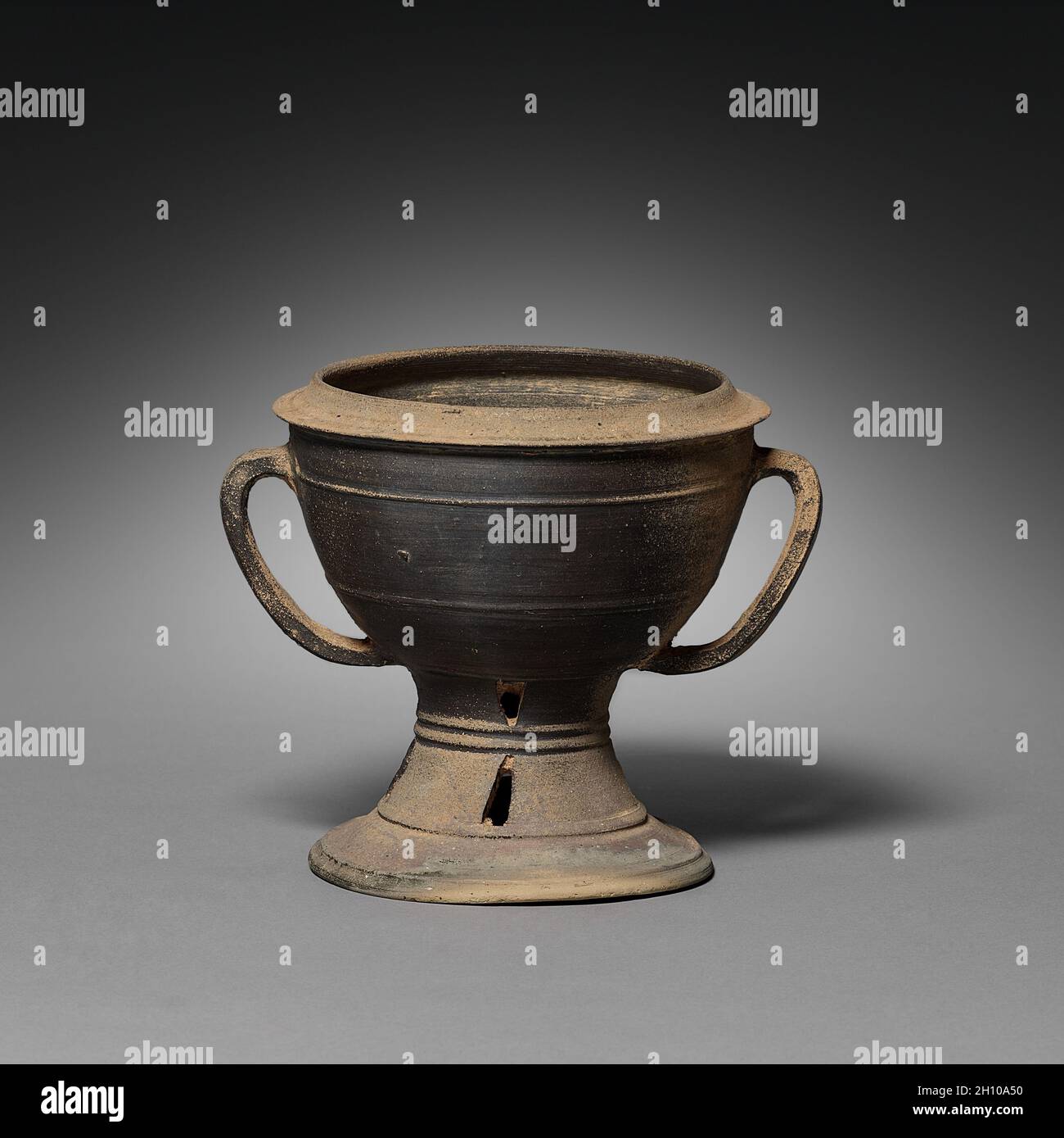 Tazza con coperchio e manici a tracolla, ad 300s-400s. Corea, periodo Kaya (ad 42-562). Gres con smalto al frassino naturale; diametro bocca: 13.5 cm (5 5/16 poll.); totale: 21.5 x 20.5 cm (8 7/16 x 8 1/16 poll.). Vasi di ceramica con un basamento del piede come questo è il primo high-fired ware conosciuto. Il suo colore grigio è il risultato della riduzione dell'ossigeno nella camera chiusa del forno. Le imbarcazioni a piedi non erano per uso quotidiano, ma servivano piuttosto a presentare offerte al defunto. Foto Stock