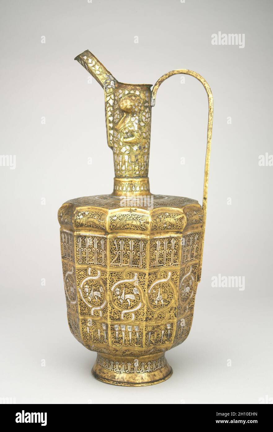 Ewer a dodici lati con Sfinge e iscrizioni a testa umana, 1300–1350. Iran, Khurasan, periodo Ilkhanid (1256-1353). Foglio martellato di ottone intarsiato con argento; totale: 44.8 cm (17 5/8 poll.). Foto Stock