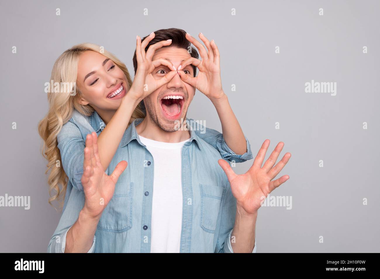 Foto di dolce divertente giovani indossare camicie denim mostrando dita occhiali occhi insenatura guardando vuoto spazio isolato grigio sfondo di colore Foto Stock