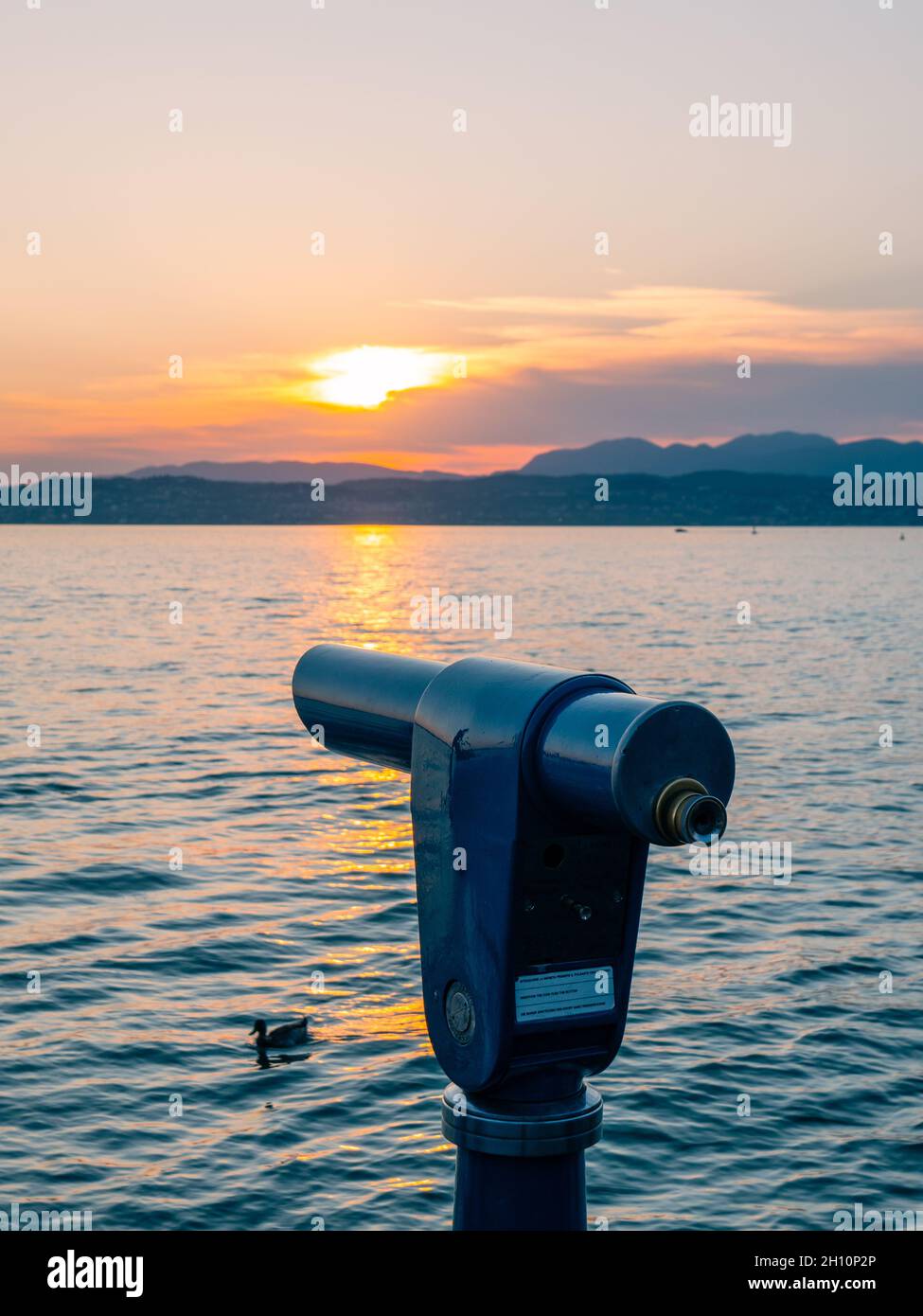 Sirmione, Italia - 9 agosto 2021: Cannocchiale e Lago di Garda al tramonto Foto Stock