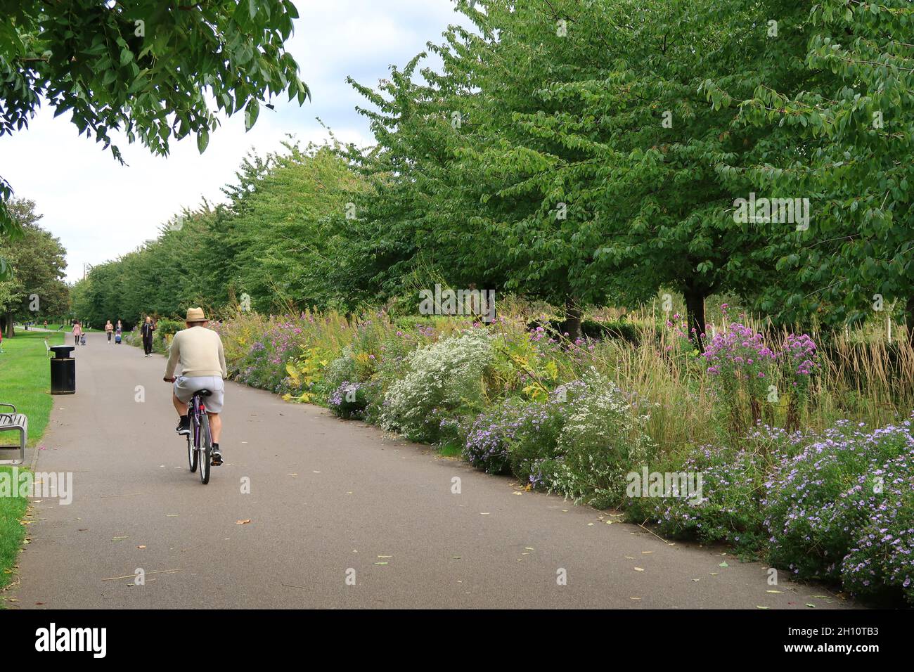 Burgess Park, Peckham, Londra, Regno Unito. Ciclisti e pedoni su un sentiero che segue la vecchia rotta del canale di Surrey. Mostra la passerella originale del canale vittoriano. Foto Stock