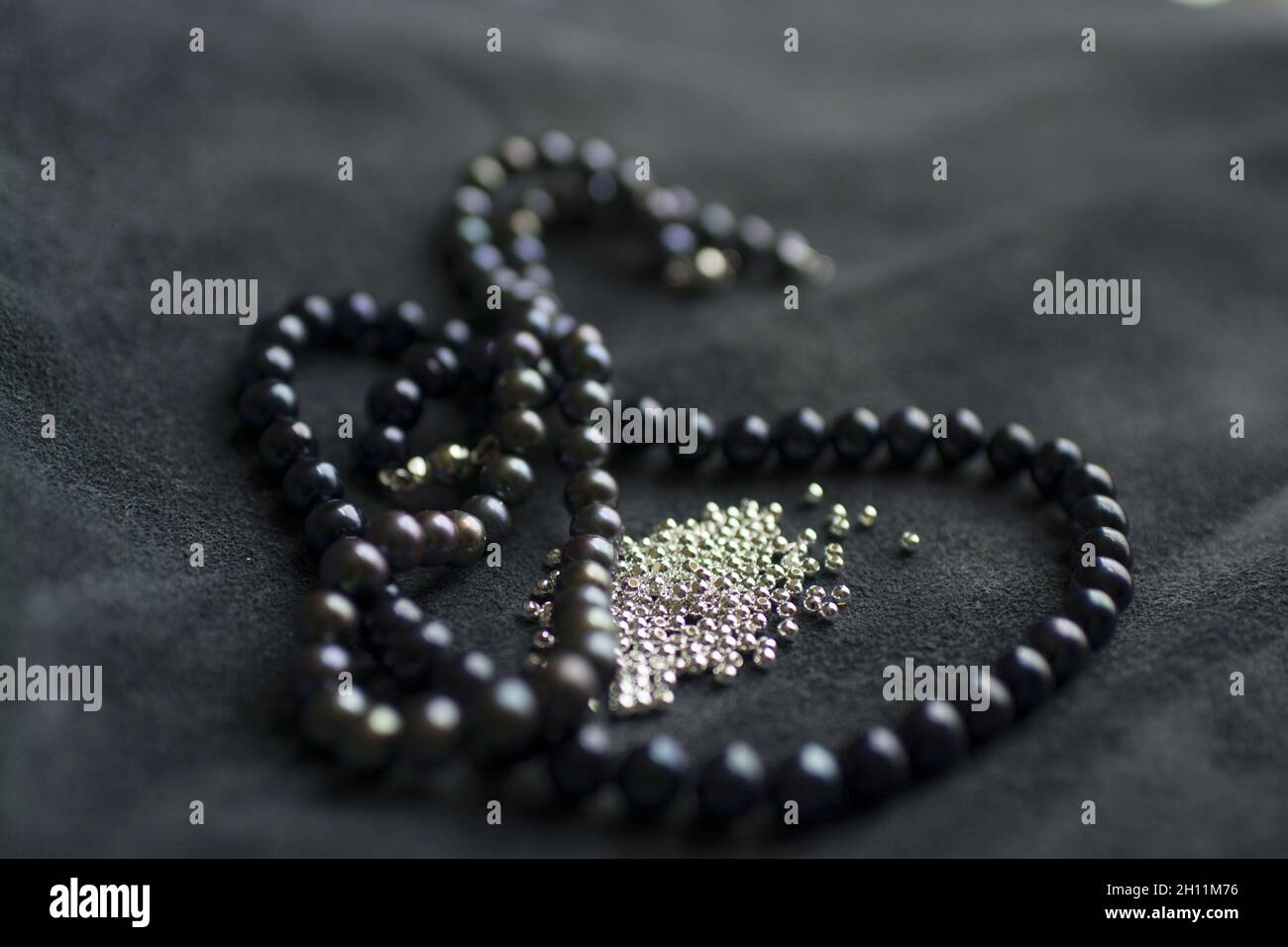 Corde di perle e teschi d'argento su sfondo di pelle Foto Stock