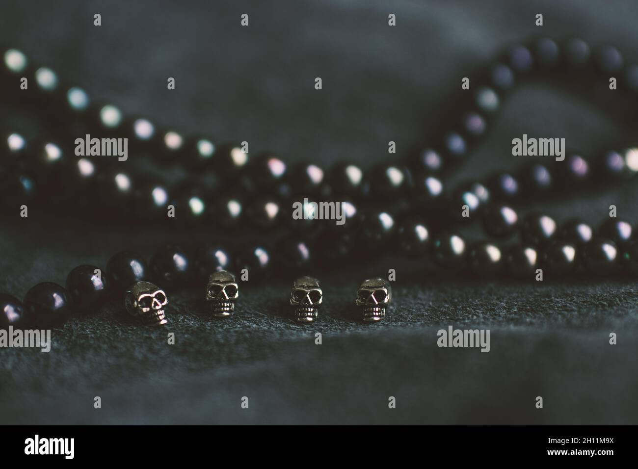 Corde di perle e teschi d'argento su sfondo di pelle Foto Stock