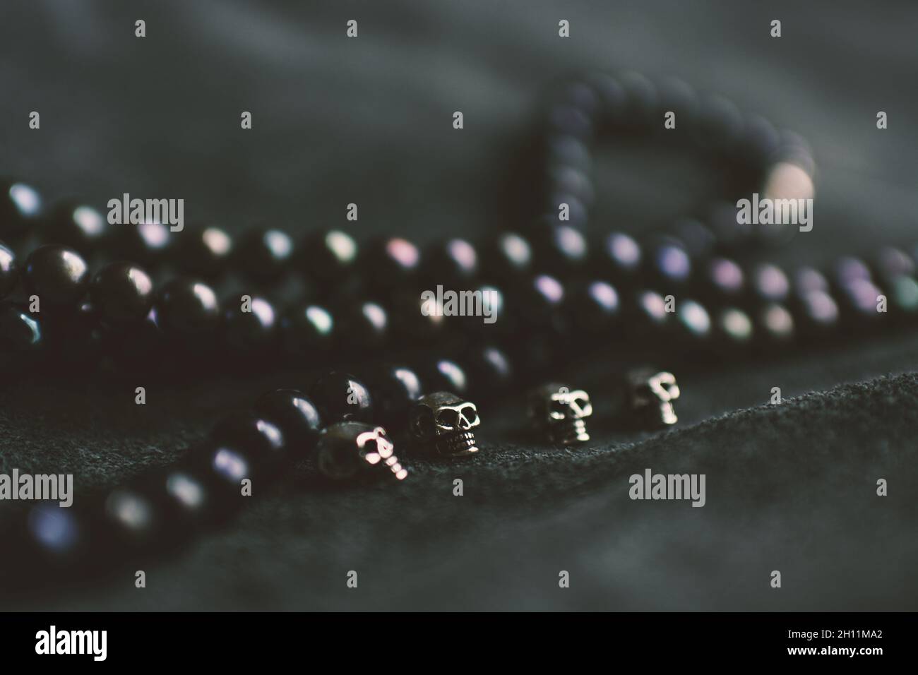 Corde di perle e teschi d'argento su sfondo di pelle Foto Stock