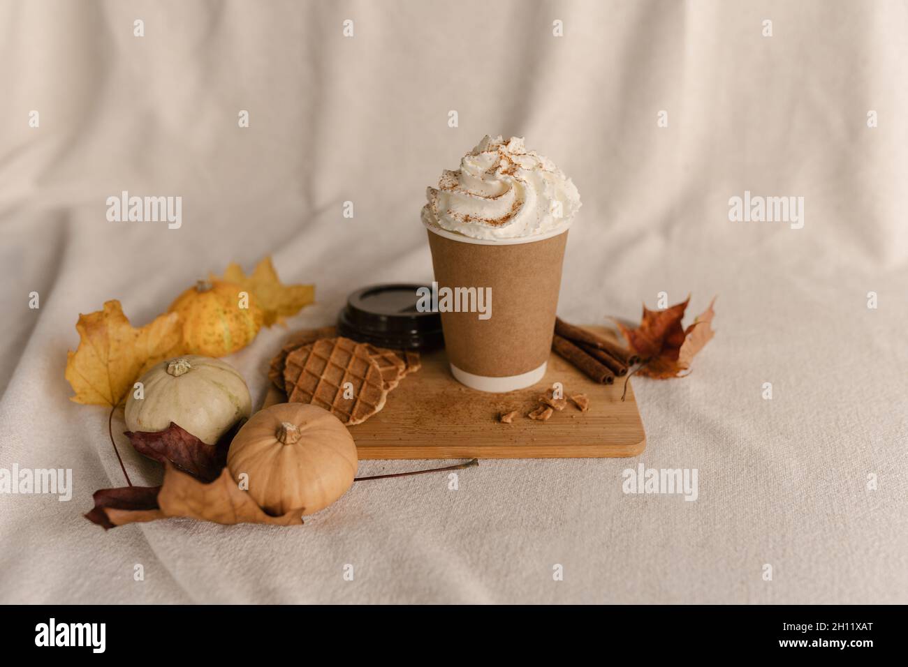 Autunno latte cannella. Caffè latte piccante di zucca. Latte di zucca speziato con panna montata e cannella fresca. Bevete nella tazza take away Foto Stock