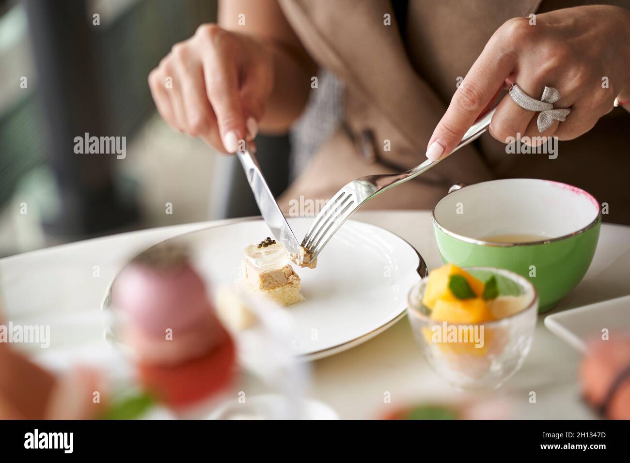 primo piano di mani di una donna asiatica cliente che mangia dessert in un raffinato ristorante Foto Stock