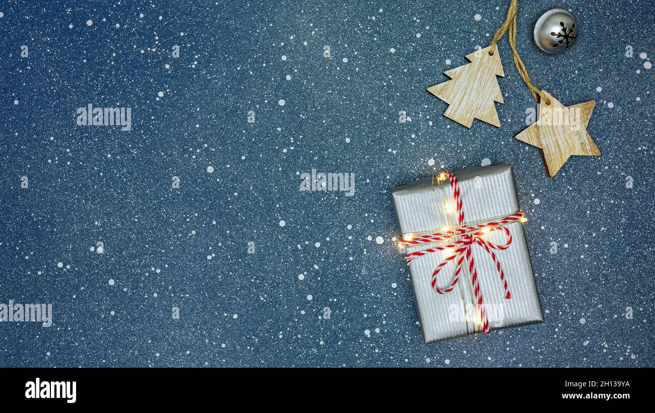 biglietto d'auguri natalizio con giocattoli in legno e campana in jingle argento su sfondo blu. Foto Stock