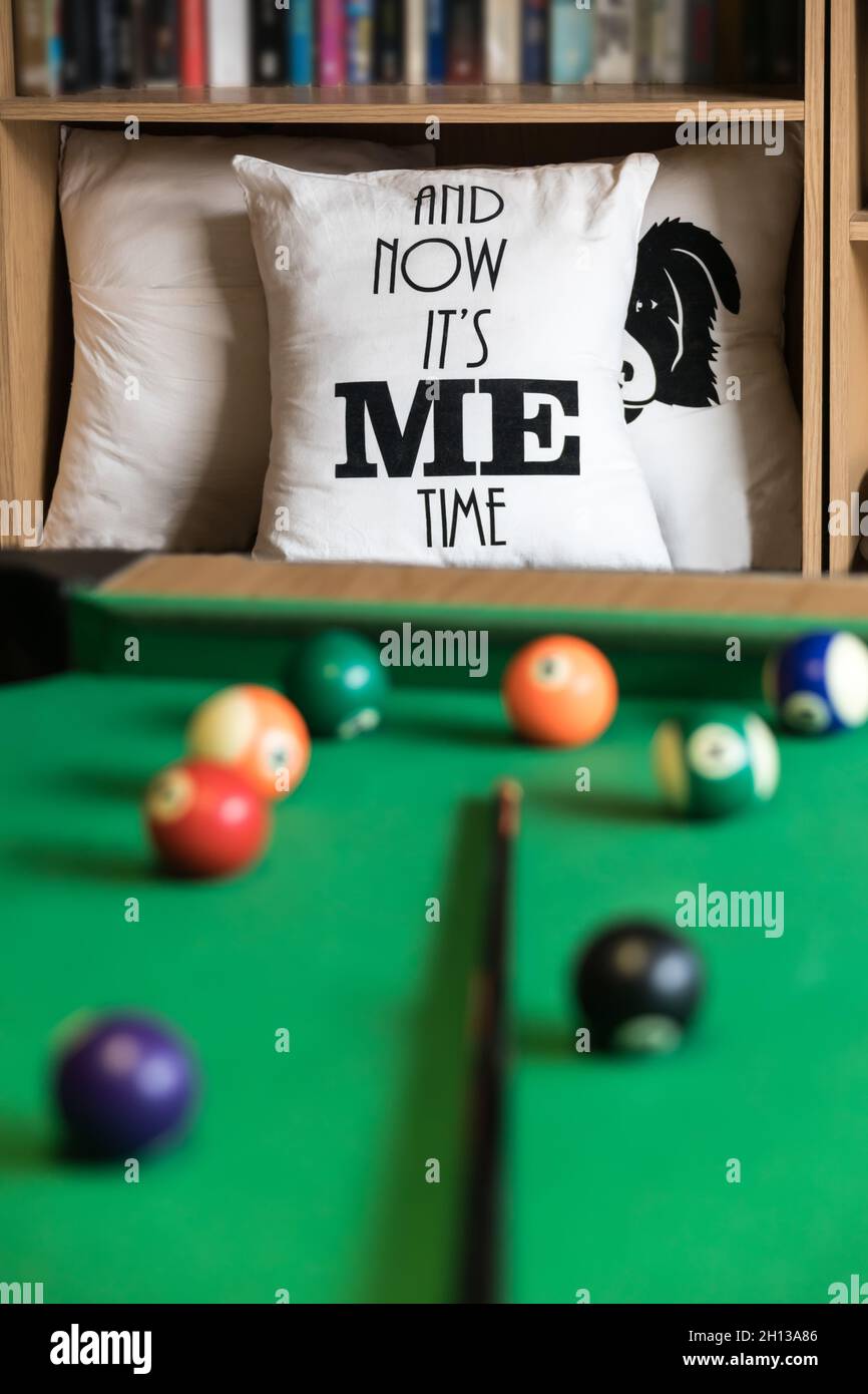 Si tratta di me il tempo tavolo da biliardo e cuscini in uno scaffale pieno di libri Foto Stock