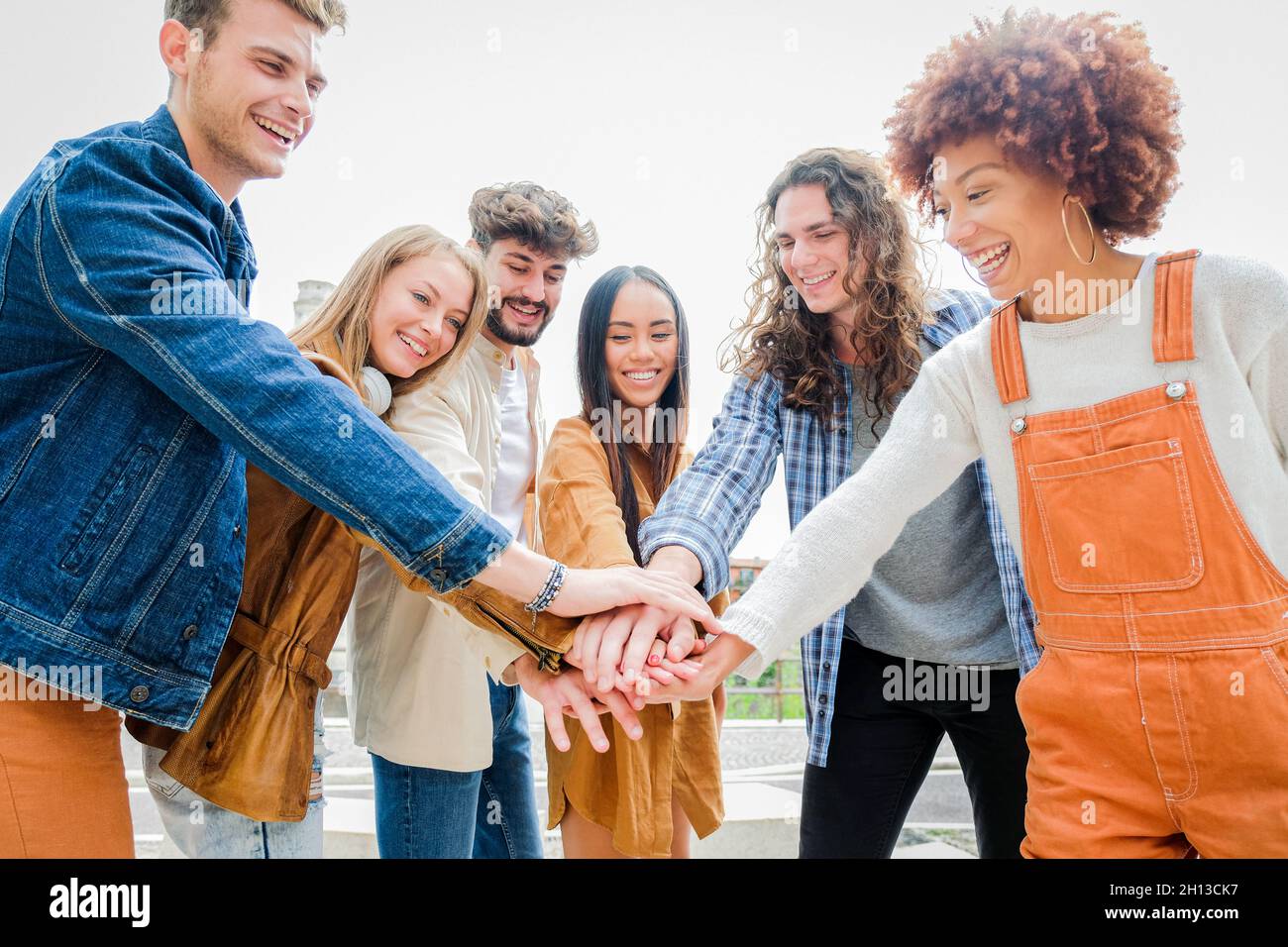 Ritratto di felici amici universitari che si accatastano le mani, mostrando unità e convivenza - studenti di cultura diversi che celebrano insieme - amici Foto Stock