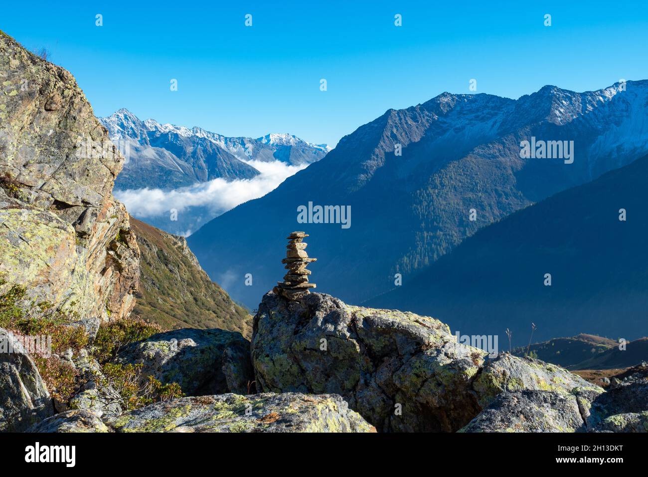Escursioni nella Svizzera Centrale. Un cairn che segna un sentiero, alte montagne sullo sfondo Foto Stock
