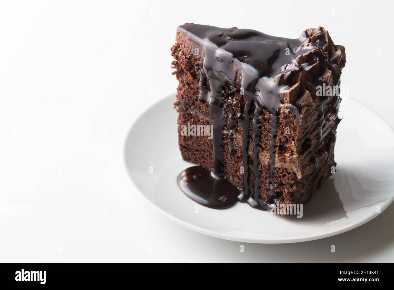 Pezzo di torta al cioccolato con salsa al cioccolato isolato su bianco con spazio copia Foto Stock