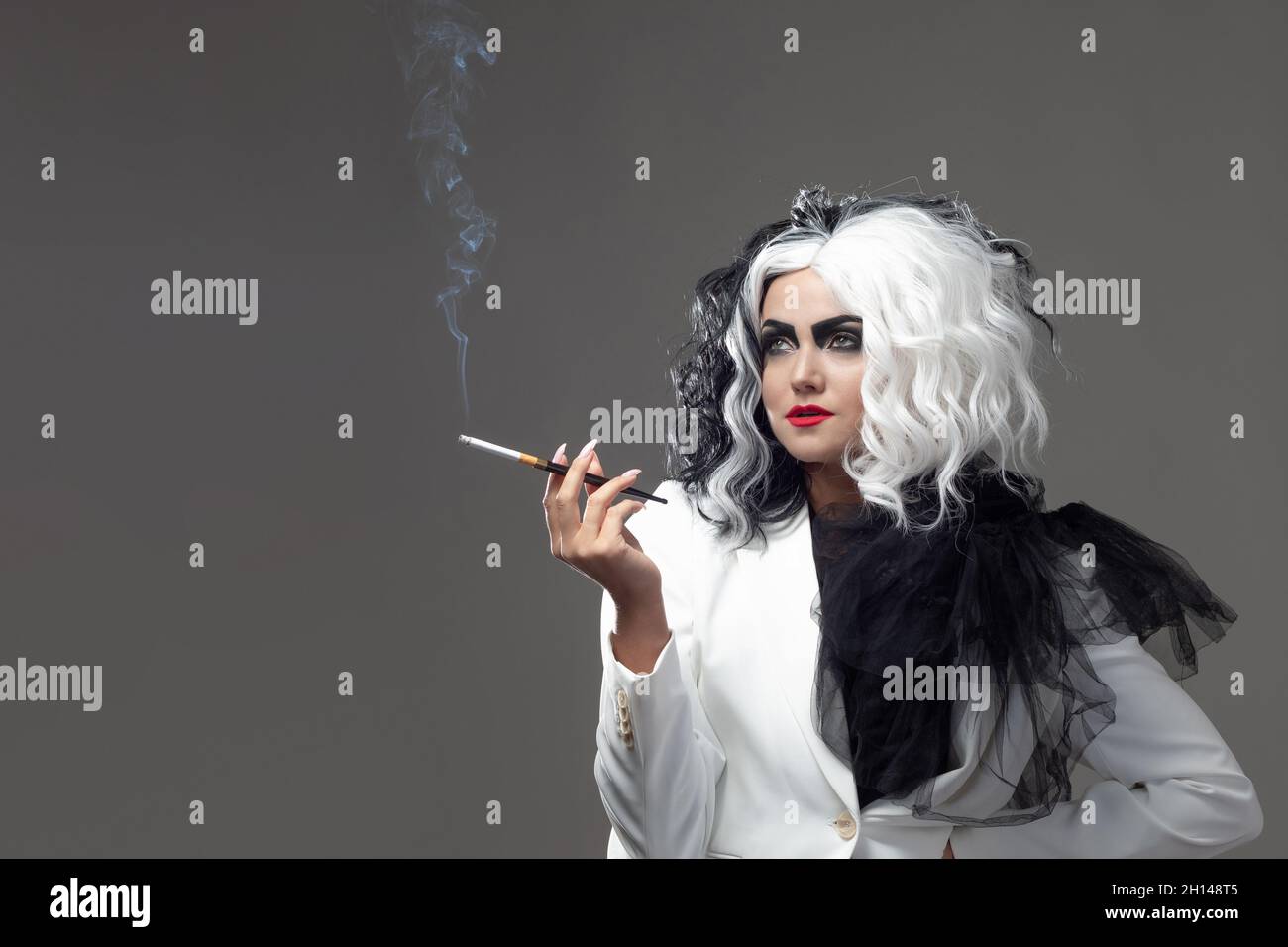 Una bellezza fatale in un'immagine di moda audace con capelli bianchi e neri. Un'immagine di stile ribelle per Halloween. Una giovane donna in un outfi bianco e nero Foto Stock