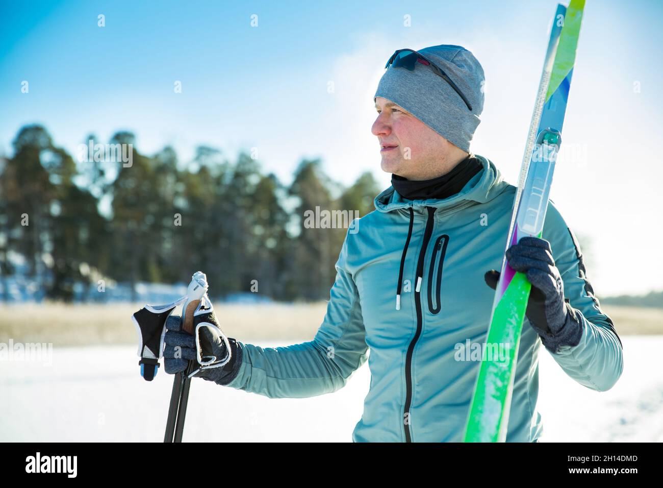 Sport invernali in Finlandia - sci di fondo. Bel fit uomo sciare in inverno soleggiato. Lago ghiacciato e foresta coperta di neve. Attività all'aperto Foto Stock