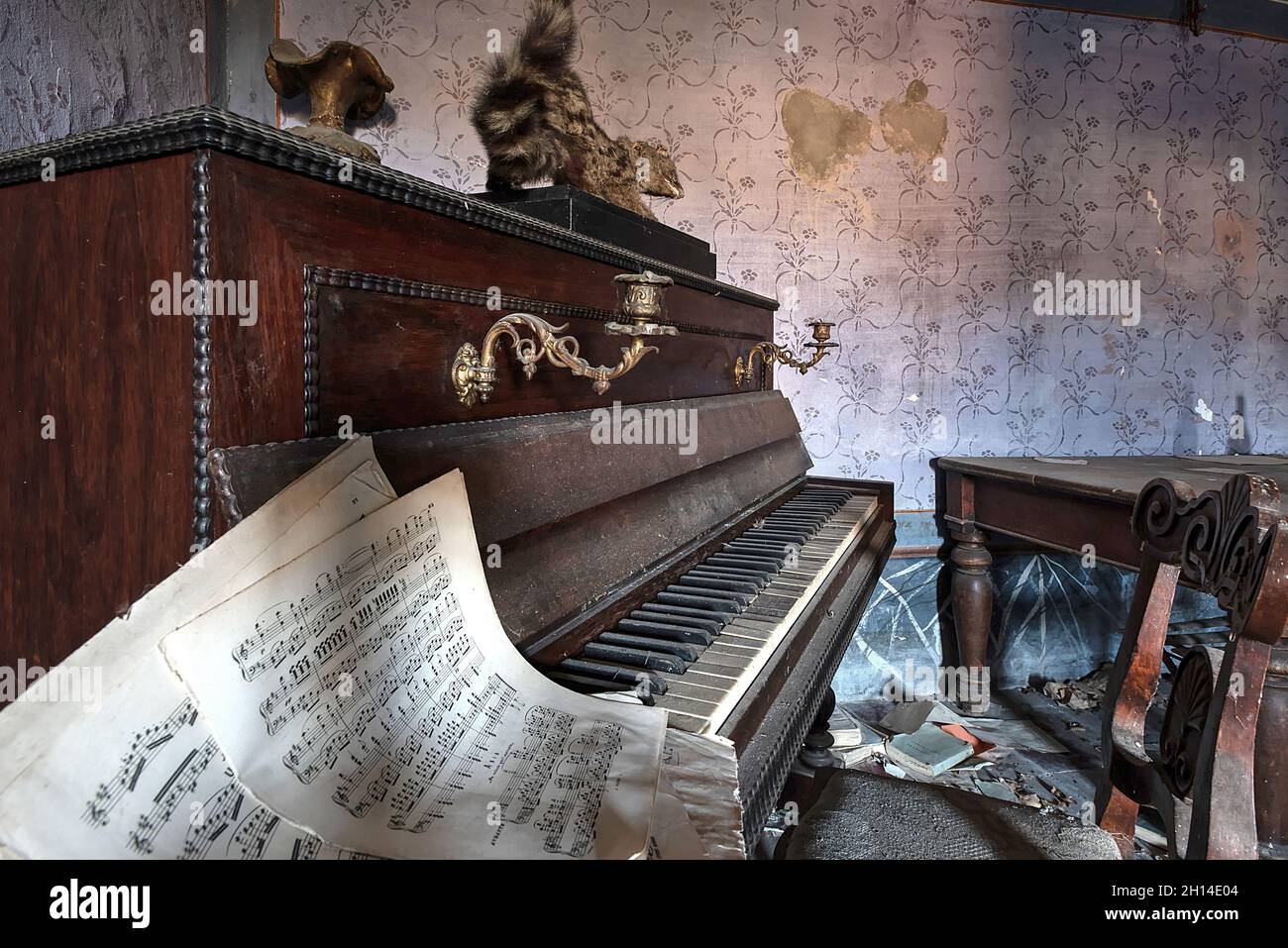Pianoforte antico con una partitura musicale, in un soggiorno di una casa abbandonata nel Nord Italia. UrbEx in Italia Foto Stock