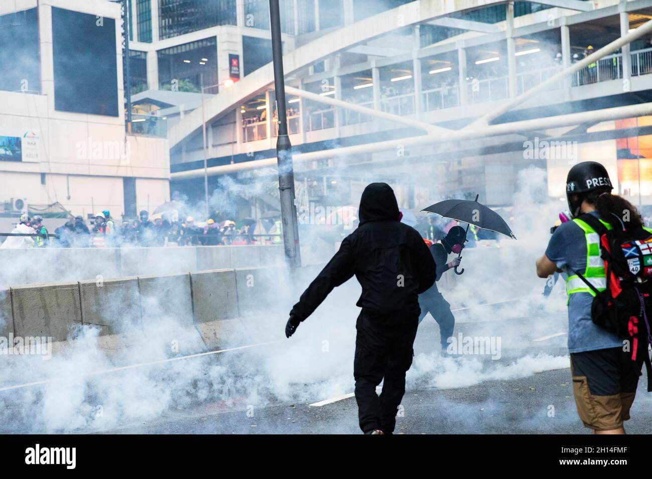 I manifestanti si coprono tra il fumo di gas lacrimogeni durante la dimostrazione.nel 2019 sono scoppiate numerose e massicce proteste a Hong Kong, poiché il disegno di legge sull'estradizione solleva gravi preoccupazioni in quanto le autorità di Hong Kong possono rinviare in Cina il convenuto senza condanna, Questa fu conosciuta come una delle più grandi avamposto civili dopo la consegna di Hong Kong in Cina nel 1997. Le proteste si sono presto aggravate a causa di manifestazioni pacifiche in scontri violenti con la polizia nel mese di luglio. Migliaia di persone sono state arrestate, ferite e ora dietro le sbarre, mentre la principale ondata di scontri si è arrestata a novembre durante i segali delle università. Giugno 2020 Foto Stock